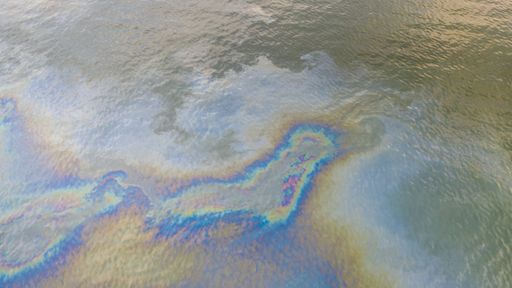 Aerial top down view to the sea surface with the rainbow-colored oil spill pattern in Tallinn city area on the Baltic Sea, Estonia