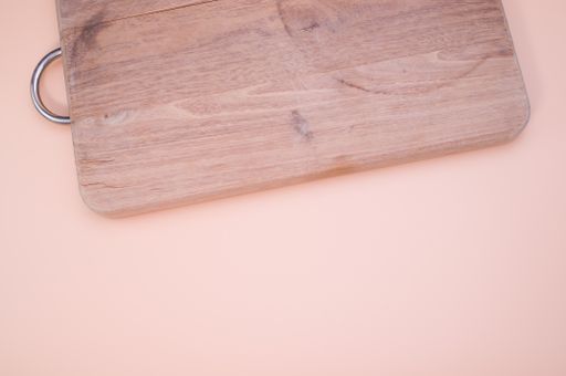 A top view of wooden chopping board isolated on light pink background with copy space