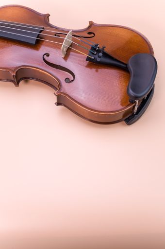 A vertical shot of violin isolated on light pink background