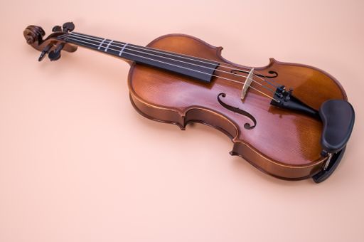 A high angle shot of violin isolated on light pink background
