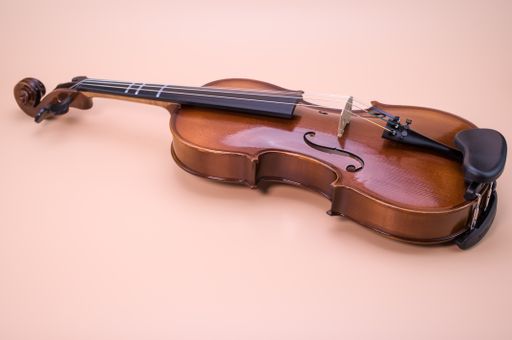A high angle shot of violin isolated on light pink background