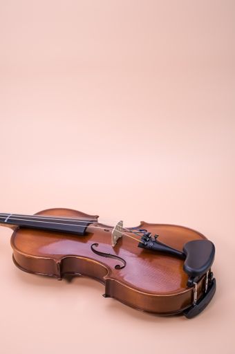 A vertical shot of violin isolated on light pink background