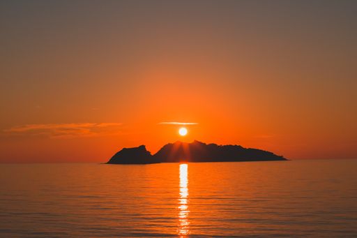 A high angle shot of seascape with sun reflection and beautiful orange skyline at sunset