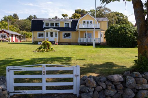 A charming yellow house with a white picket fence and a well-maintained garden on a sunny day.