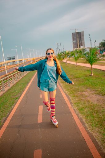 A vertical shot of a young Hispanic female in a retro roller skating outfit on a trail