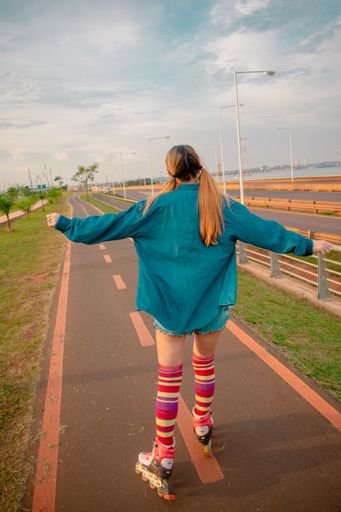 A vertical shot of a young Hispanic female in a retro roller skating outfit on a trail