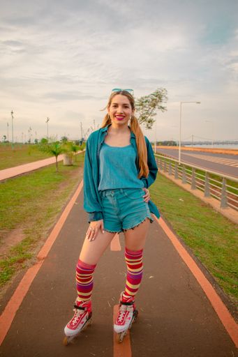 A vertical shot of a young Hispanic female in a retro roller skating outfit on a trail