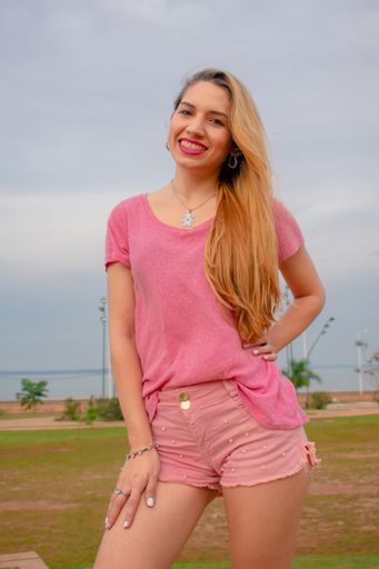 A vertical shot of a young Hispanic female in a pink summer outfit