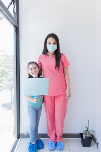 A vertical shot of a girl with the dentist in a dental office, receiving dental treatment.