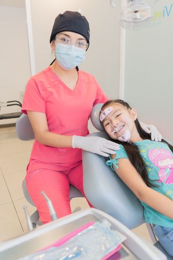 A vertical shot of the doctor and a girl who received dental treatment for the care of her teeth.