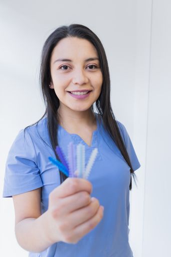 A vertical closeup of a young female dentist at her office offering different types of dental services.