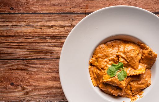A top shot of cooked salmon ravioli pasta in a bowl on the side with copy space.