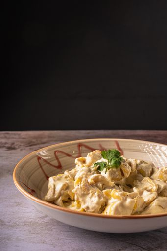 A vertical shot of cooked pear Fiocchetti on a plate on a black background.