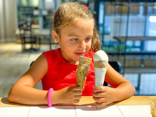 A happy Caucasian girl smiling with two ice cream in her hand