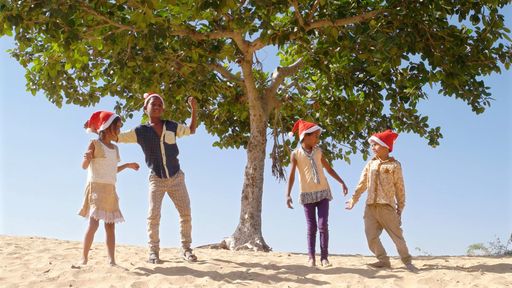 Happy Indian female and male kids celebrating New Year in Santa Claus hats on a beach