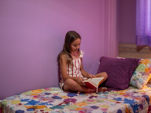A pretty Spanish girl is spending leisure time with a book in her room