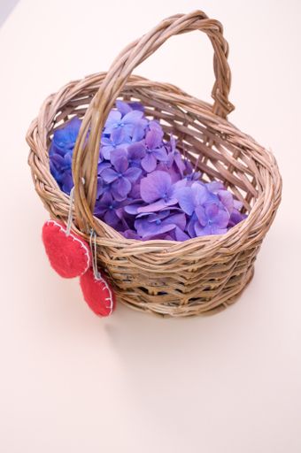 A vertical shot of purple hydrangea flowers with heart-shaped objects on a woven basket