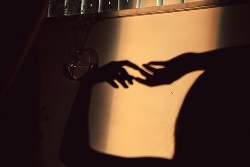The shadow of the two hands touching each other on the wall