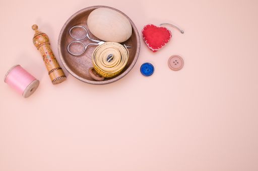 A closeup shot of stitching materials on a wooden bowl isolated on a pink background