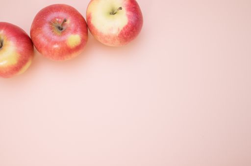 A closeup shot of fresh apples isolated on pink background with copyspace