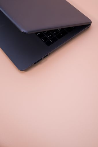 A vertical shot of a black laptop isolated on a pink background with copy space