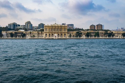 The Dolmabahce palace surrounded by buildings and the sea under a cloudy sky in Istanbul in Turkey