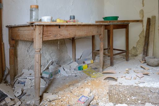 An old wooden table with broken pieces of stone and wood around it in an abandoned rustic farm