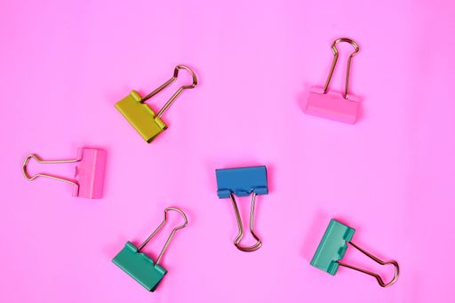 A bunch of colorful office clips on a pink background