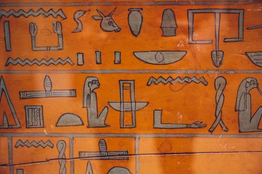 An ancient Egyptian relic in the Egyptian Museum in Cairo with gray painted hieroglyphs on an orange background