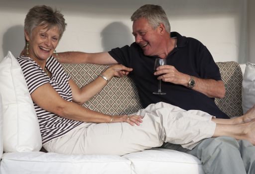 A happy husband and wife sitting together on the sofa and smiling