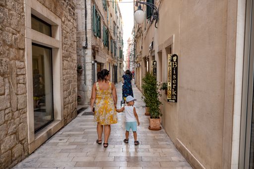 A woman and kids walking on a narrow street in the city center of Sibenik, Croatia
