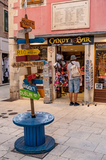 A vertical shot of direction signs and a candy shop in the city center of Sibenik, Croatia