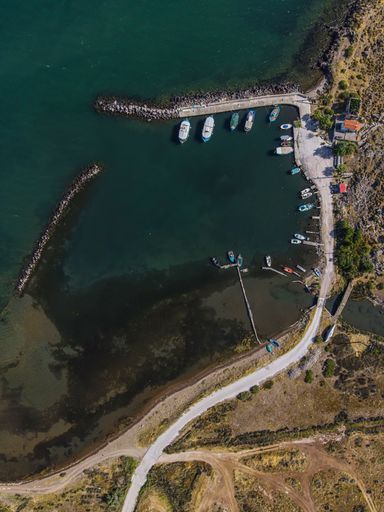 A bird's eye view of a road beside the sea leading to the shore with boats at the docks