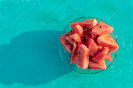 A top view of watermelon cut on pieces in a glass plate on a blue background