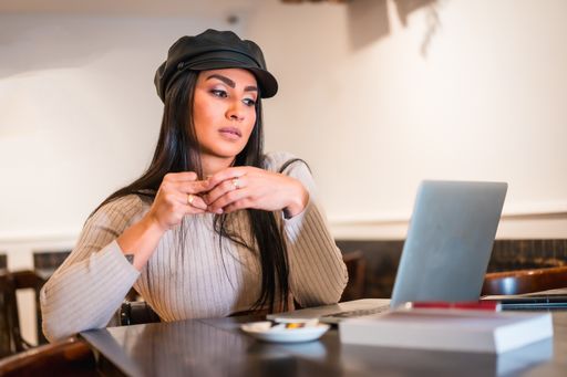 A closeup of a smart Hispanic woman working on her laptop in a cafe with a diary in front of her