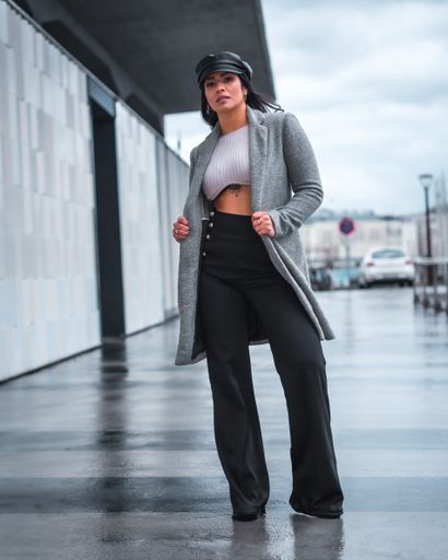 A vertical shot of a fierce Latina posing on a rainy autumn day with a large gray overcoat o
