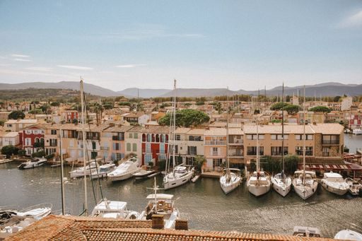 Scenic view of a marina with colorful buildings and boats docked in a quaint town under a clear blue sky.