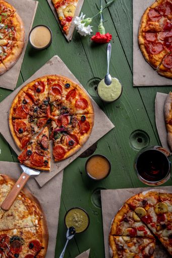 Tasty pepperoni pizza and cooking ingredients tomatoes basil on black concrete background. Top view of hot pepperoni pizza. With copy space for text.