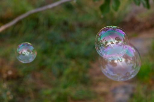 A close-up of soap bubbles floating in the air with reflections of trees and sky in the background