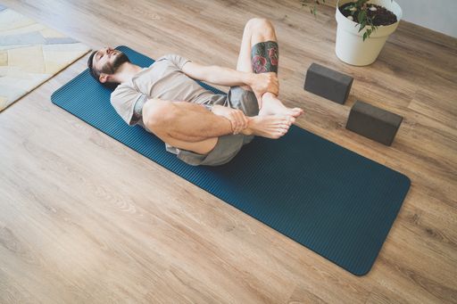 A Bulgarian Caucasian man doing yoga on his mat indoors