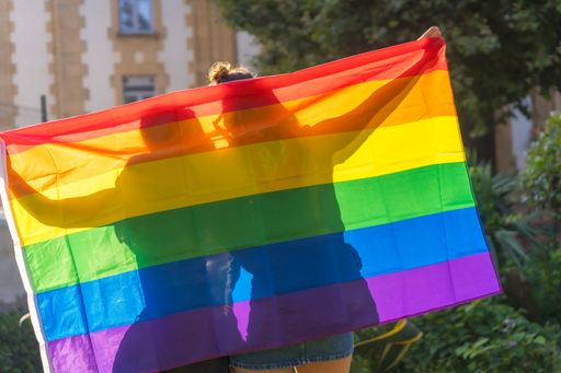 A closeup shot of two young Caucasian females holding LGBT pride flag outdoors