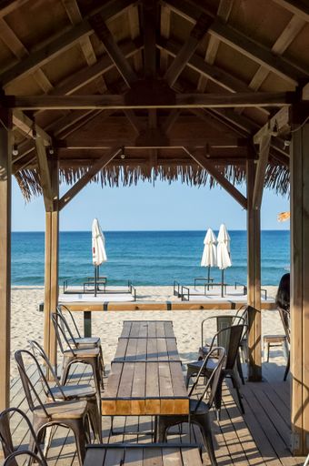 A vertical shot of a sandy beach cafe with wooden table and chairs in the bungalow