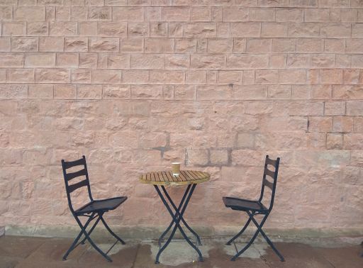 The two chairs and a wooden table with a brick wall on the background