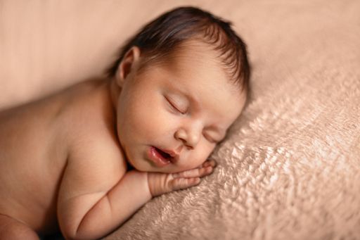 A closeup shot of an adorable sleeping baby on a fluffy surface
