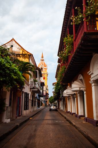 A colorful street in Cartagena, Colombia during the early morning. The famous yellow and pink church stands in the distance.