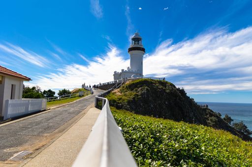 A scenic view of Cape Byron Lighthouse in New South Wales, Australia, with a clear blue sky and ocean in the background.