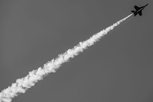 A black and white image of a jet leaving a trail of smoke in the sky, showcasing speed and precision.