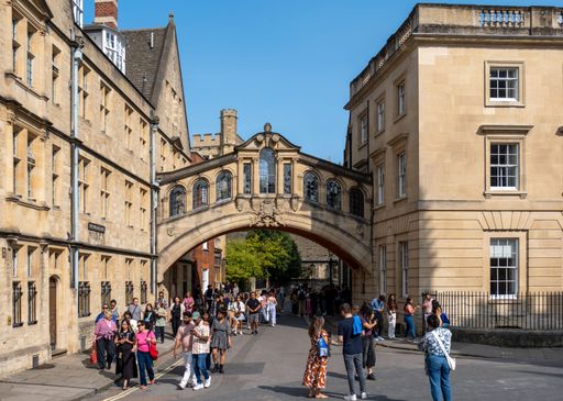 The tourists walking under the Bridge of Sighs connecting two parts of Hertford College on a sunny daytime with clear sky