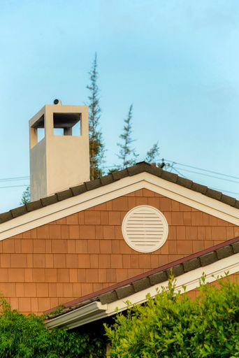 A vertical shot of a modern residential building with a chimney under a clear sky