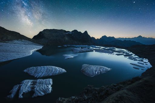 Summer nightscape view of icebergs floating on a mountain lake with the milky way above